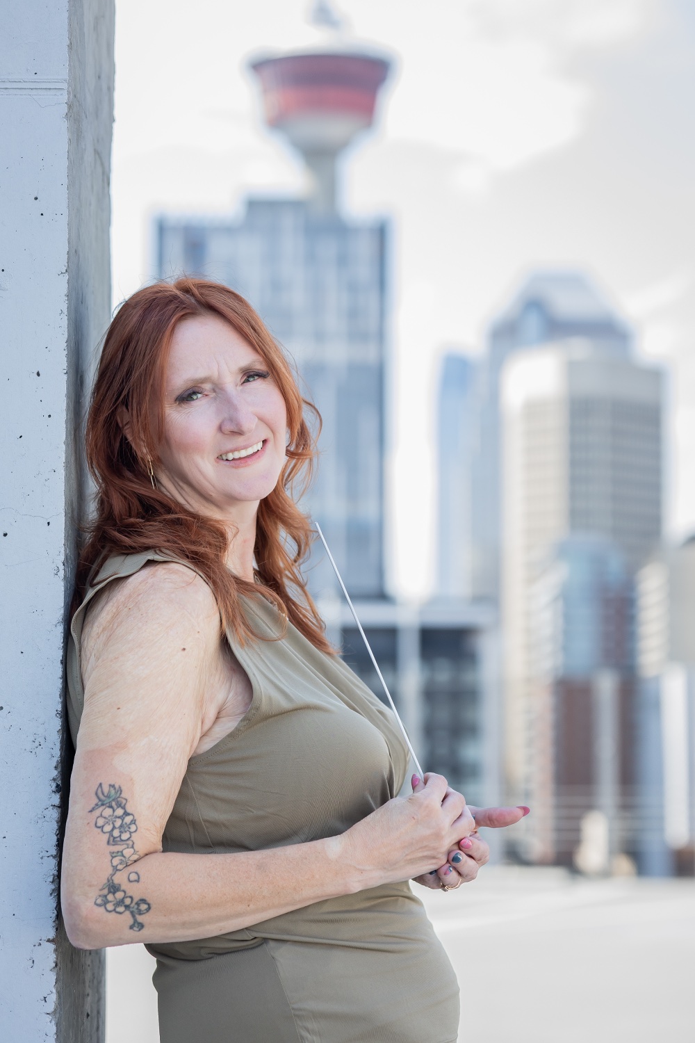 Sarah Batchelor holding a conducting baton with a city skyline behind her